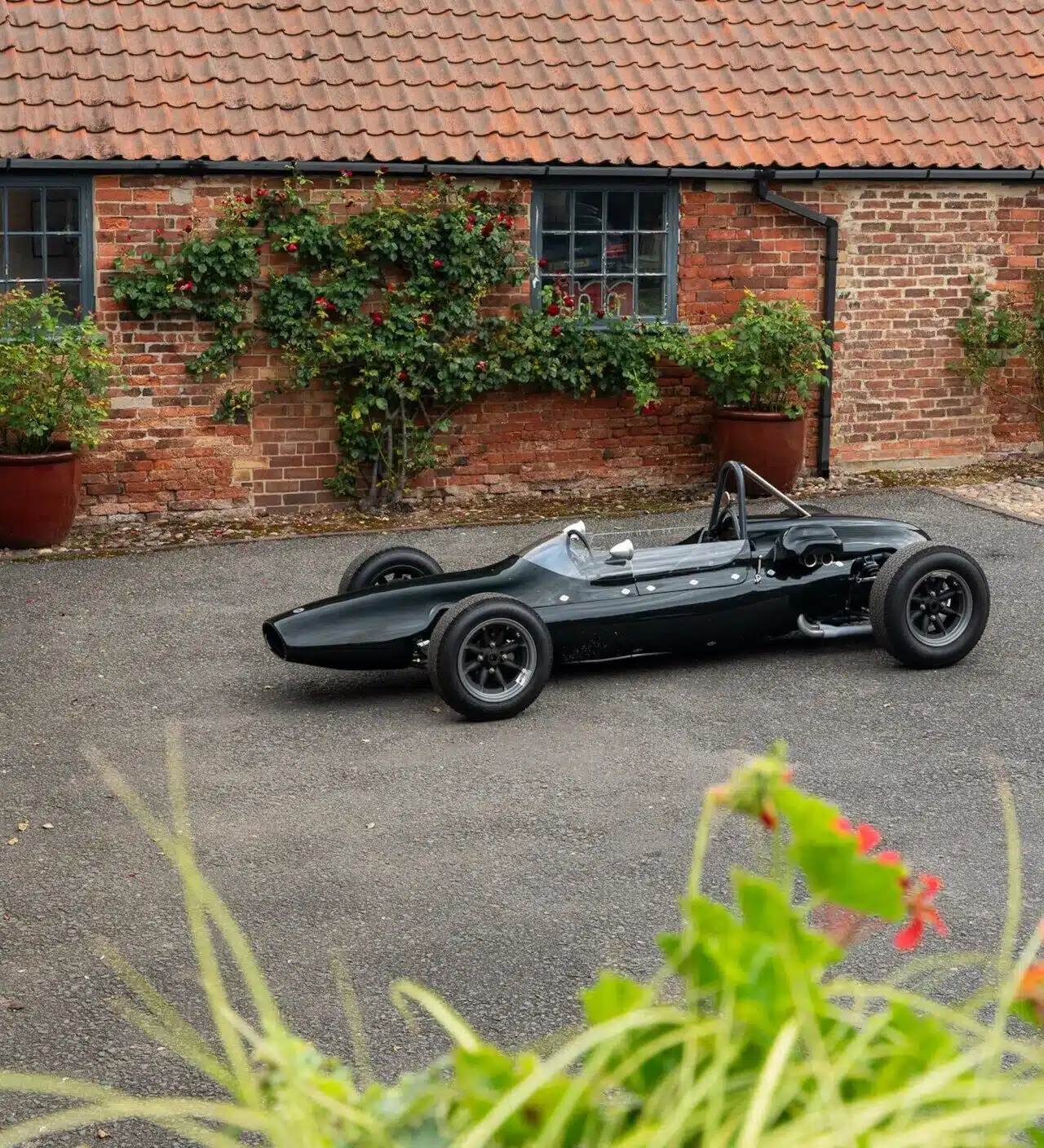 Cooper T59 Formula Junior von 1962 in dunkelgrüner Lackierung, seitlich aufgenommen vor einem Backsteingebäude.