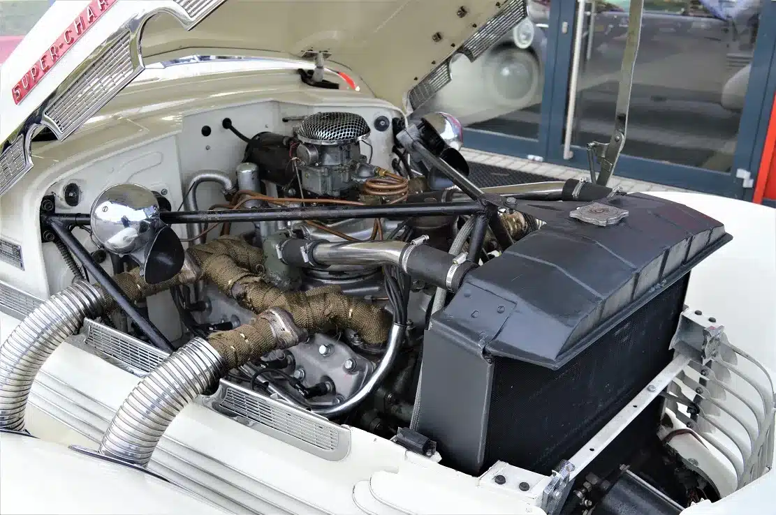 Geöffnete Motorhaube des Cord 812 Supercharged Convertible Phaeton mit sichtbarem Kompressor und Motorstruktur