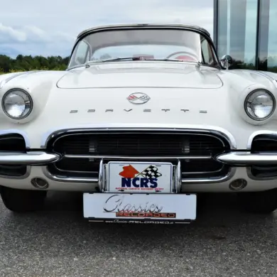 Weiße Corvette C1 Roadster 327 Dual Top, Baujahr 1962, von vorne aufgenommen, mit sichtbarem Emblem und Hardtop.