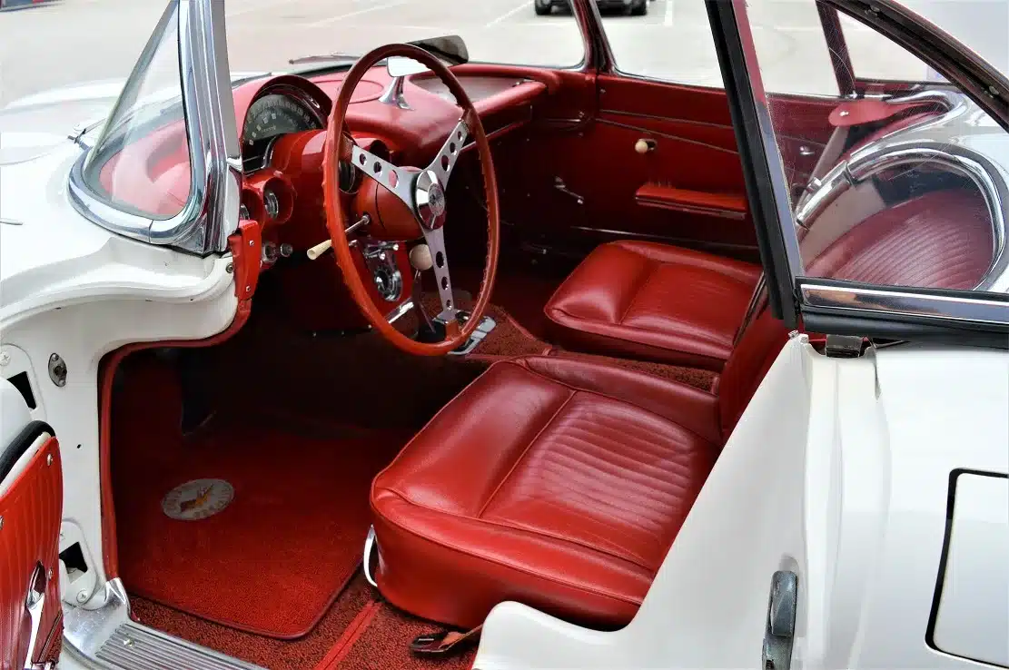 Roter Innenraum einer Corvette C1 Roadster 327 Dual Top von 1962 mit Blick auf das Lenkrad und Armaturenbrett.