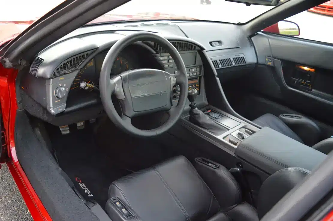 Innenraum einer Corvette ZR1 C4 LT5 von 1990 mit schwarzen Sportsitzen und Cockpitansicht.