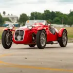 Frontansicht eines roten Dagrada Giannini Fiat 750 Sport von 1949 mit charakteristischem mittigen Scheinwerfer auf einem Flugplatz.