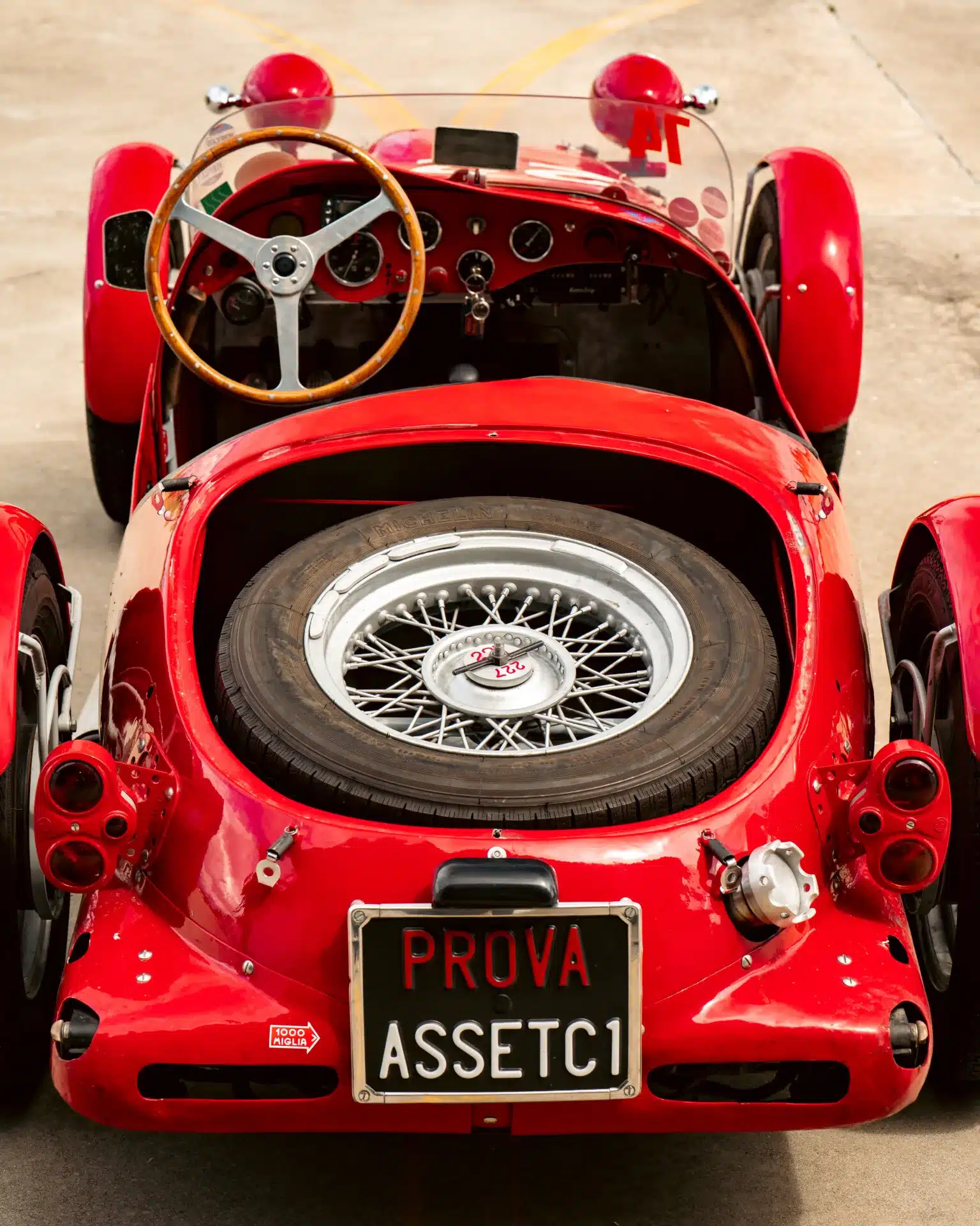 Cockpit, Lenkrad und Reserverad im Heck eines klassischen roten Dagrada Giannini Fiat 750 Sport von 1949.