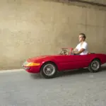 Ein Mann fährt ein rotes, maßstabsgetreues Junior-Car-Modell Daytona, das optisch klassischen Sportwagen nachempfunden ist.