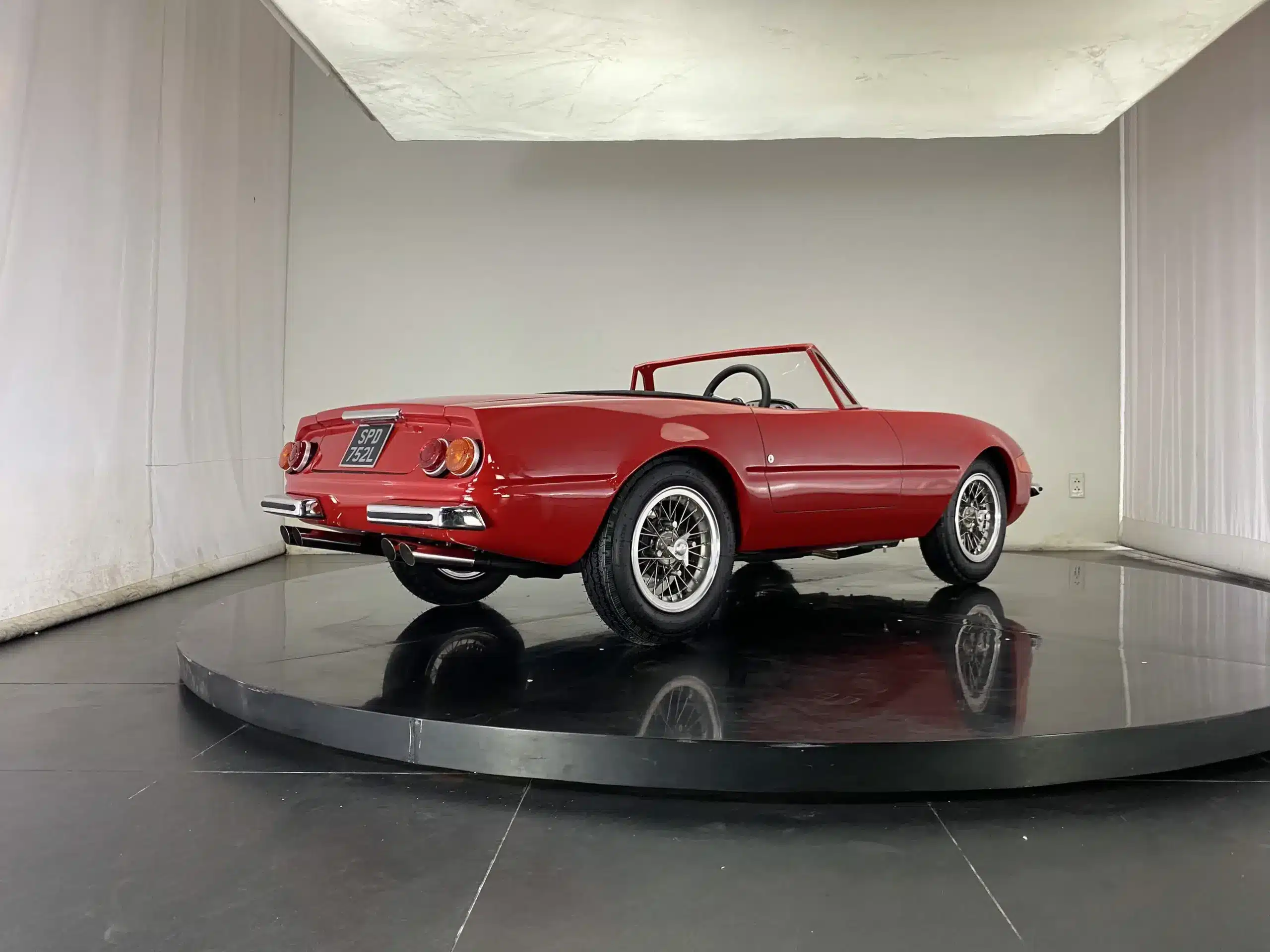 Das Junior-Car Daytona von Junior Cars UK in rotem Lack, als Zweisitzer aus der Rückansicht, ausgestellt auf einer Drehbühne.