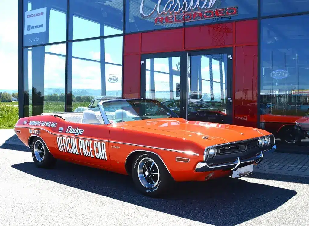 Dodge Challenger Convertible Pace Car von 1971 in Hemi Orange mit offizieller Pace Car Beschriftung, vor einem Showroom geparkt.