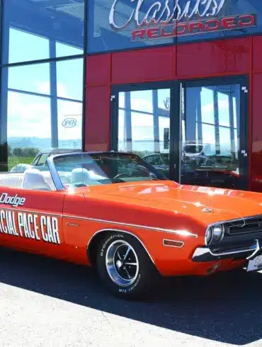 Dodge Challenger Convertible Pace Car von 1971 in Hemi Orange mit offizieller Pace Car Beschriftung, vor einem Showroom geparkt.