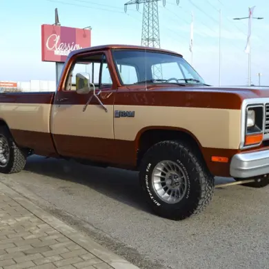 Dodge D150 Ram Frame-Off von 1984 in Western Brown Metallic und Creme, Seitenansicht auf Parkplatz.