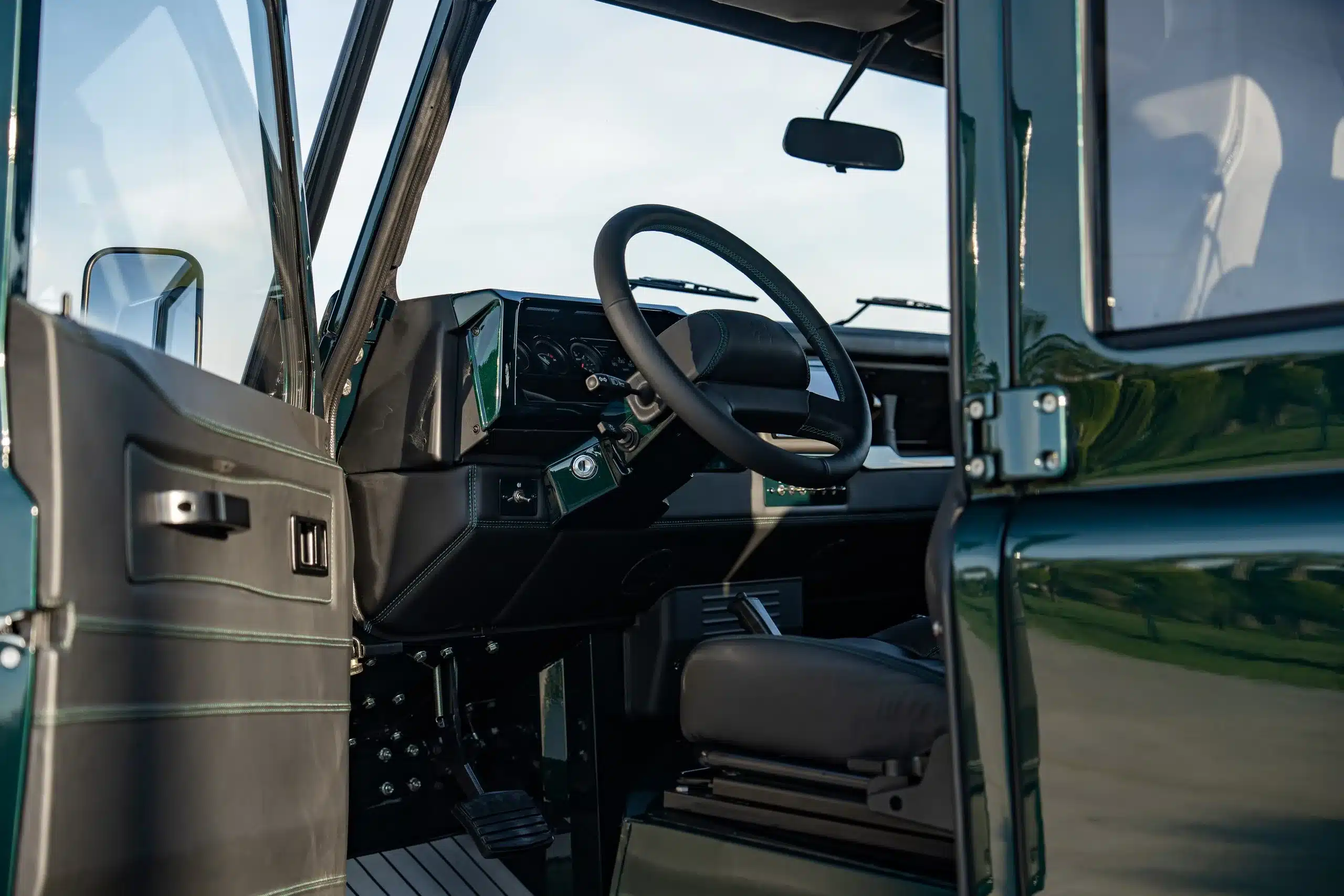 Cockpit und Lenkrad eines Land Rover Defender 110 (1989) mit geöffneter Tür, Innenansicht