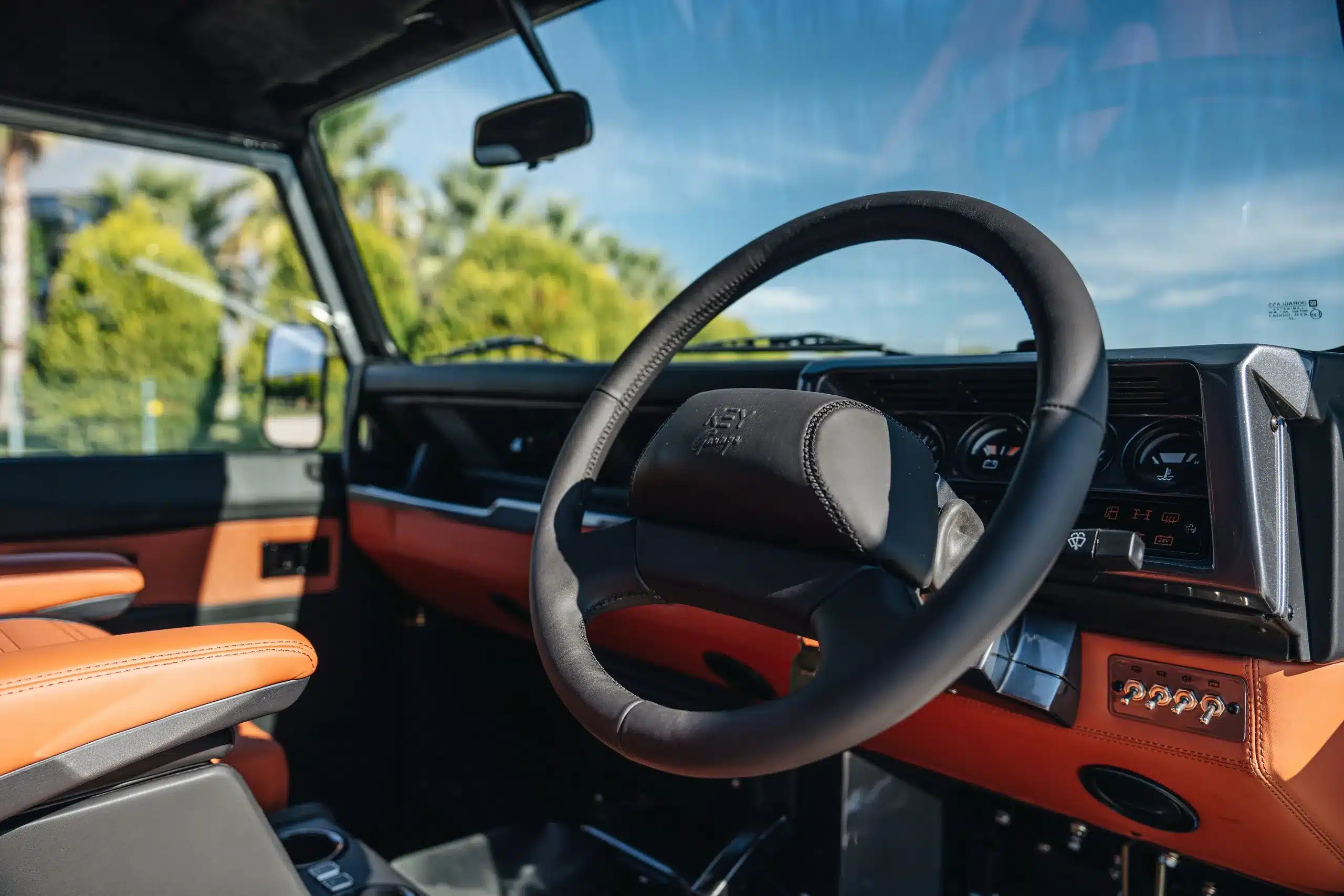 Innenraum und Armaturenbrett eines elektrifizierten Land Rover Defender 110 (Baujahr 1989) mit Lederlenkrad und moderner Ausstattung.