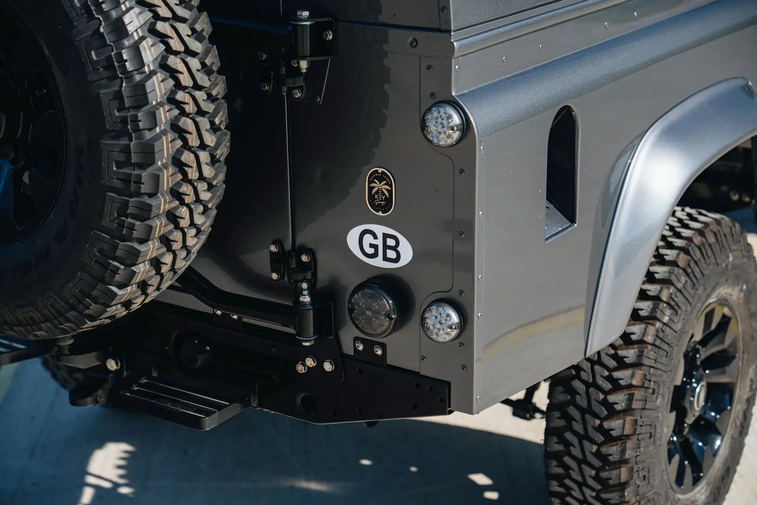 Corris-grauer Land Rover Defender 110 (Baujahr 1989) mit Reserverad und Detailansicht des hinteren Kotflügels.