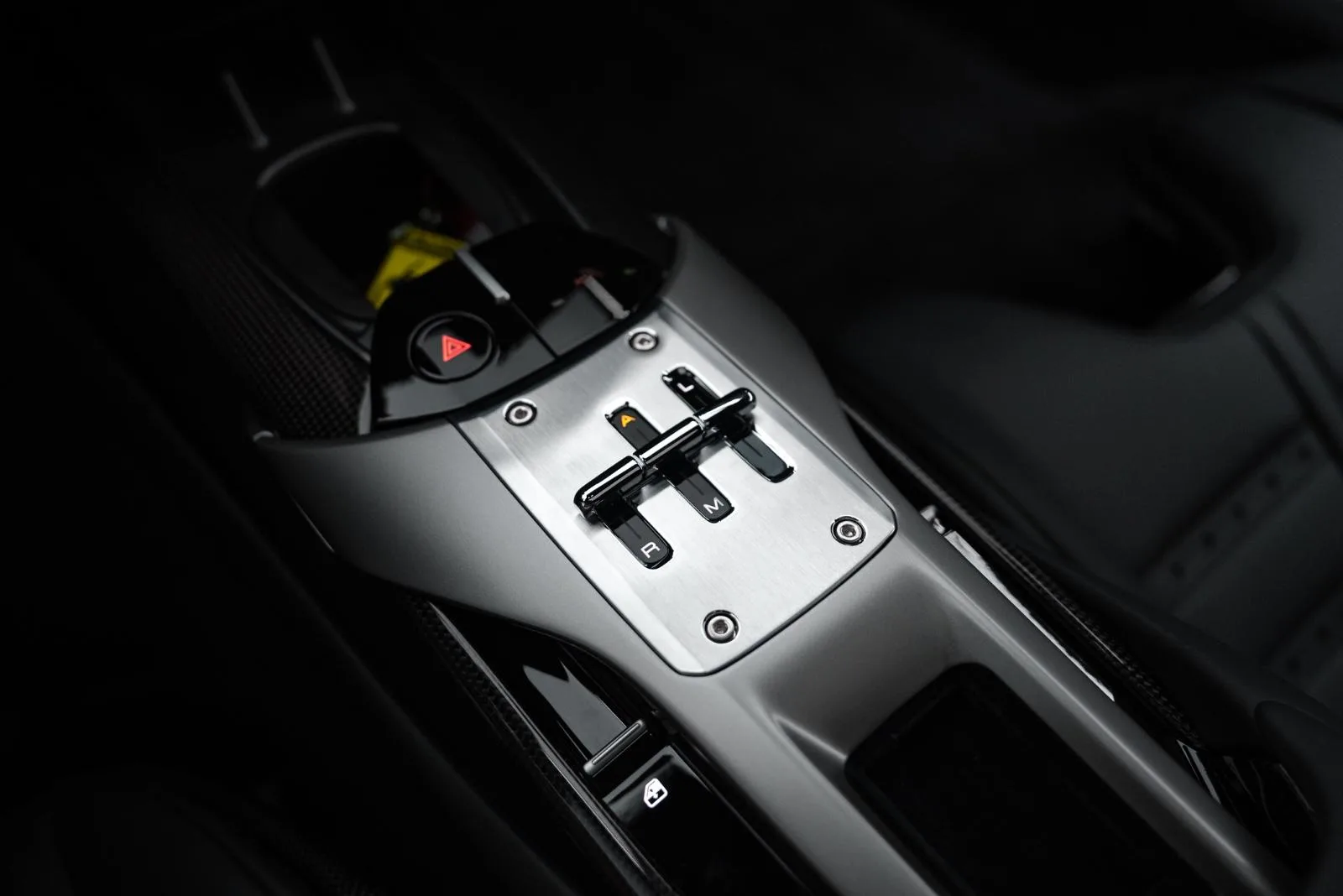 Mitteltunnel eines Ferrari 12Cilindri mit Schaltknöpfen und metallischer Oberfläche im Innenraum