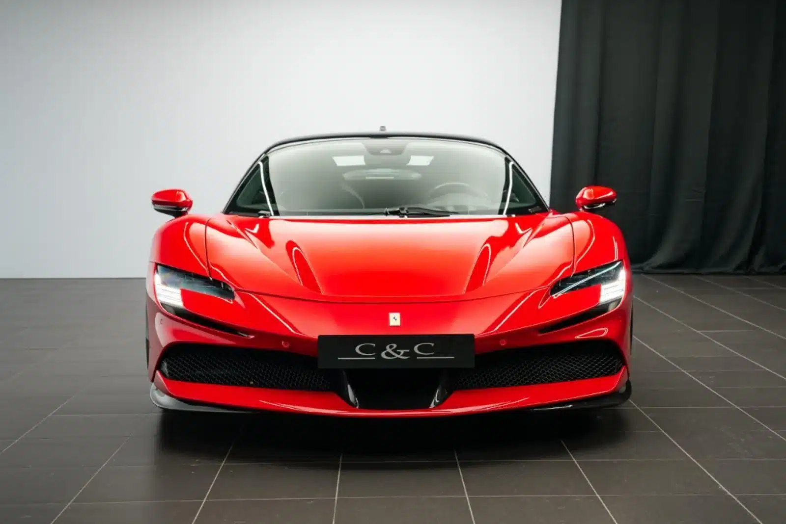 Ferrari SF90 Stradale Fiorano in Rot mit schwarzem Dach, Frontansicht im Showroom.