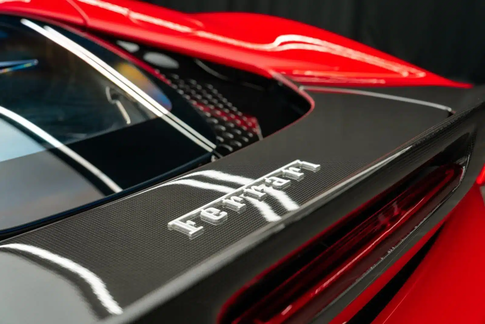 Nahaufnahme des Ferrari-Logos auf dem Carbon-Heckspoiler und der Motorabdeckung des Ferrari SF90 Stradale Fiorano in Rot und Schwarz