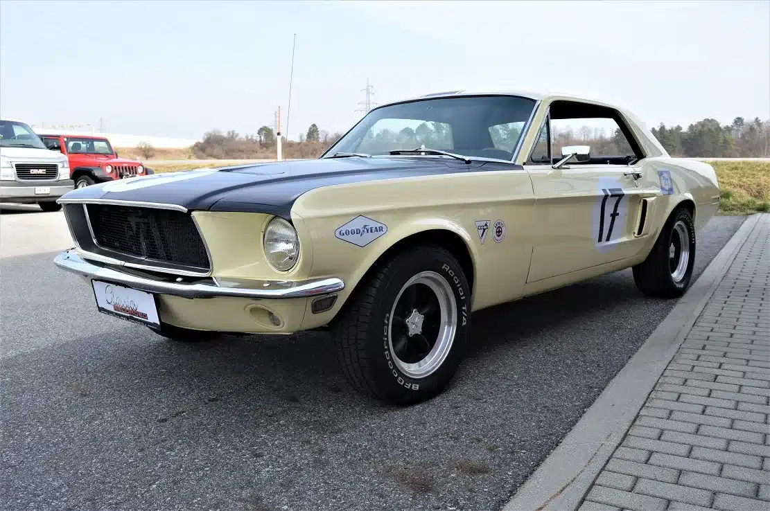 Ford Mustang Shelby Terlingua 302 Baujahr 1968 in gelber Lackierung mit schwarzen Rennakzenten und Original-Racing-Logos, schräg von vorne fotografiert.