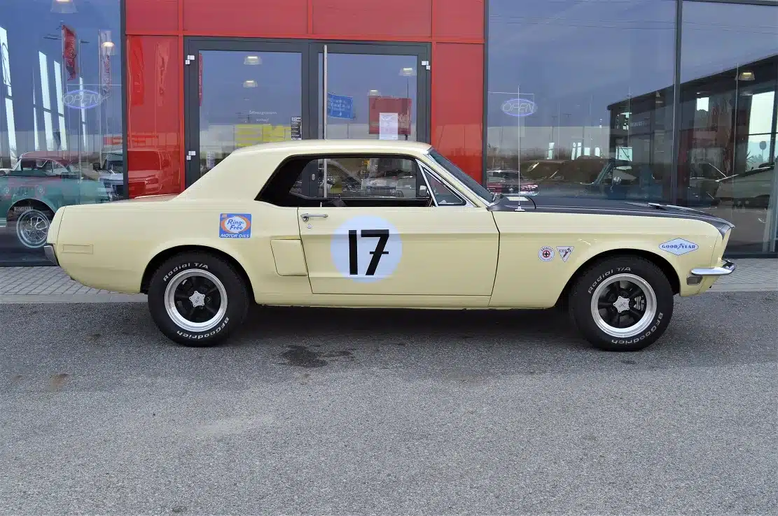 Ford Mustang Shelby Terlingua 302 in gelb-schwarzer Lackierung mit Startnummer 17 und Rennsport-Aufklebern, geparkt vor einem Autohaus.