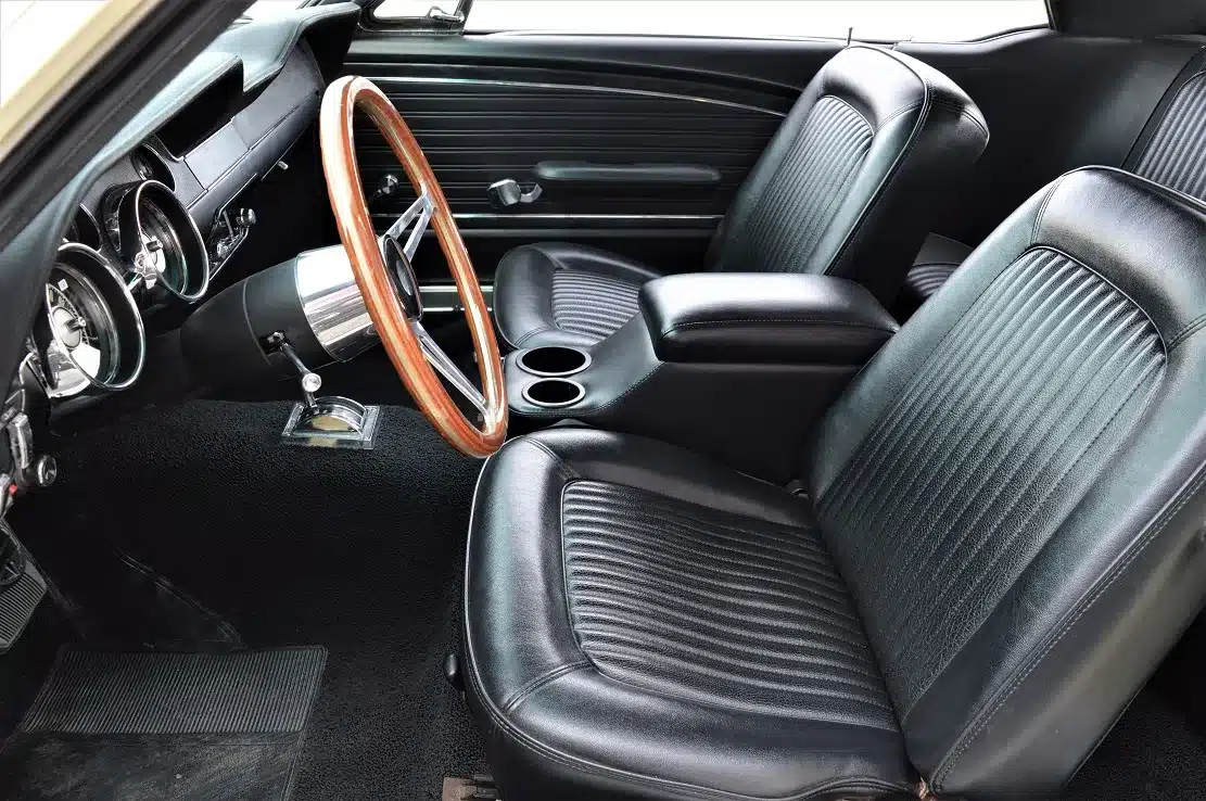 Innenraum eines Ford Mustang Shelby Terlingua 302 von 1968 mit schwarzen Sitzbezügen und Holzlenkrad
