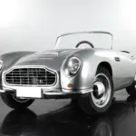 Detailgetreues Kinderauto GB Spirit im Stil eines klassischen britischen Sportwagens, präsentiert in Silber vor neutralem Hintergrund.