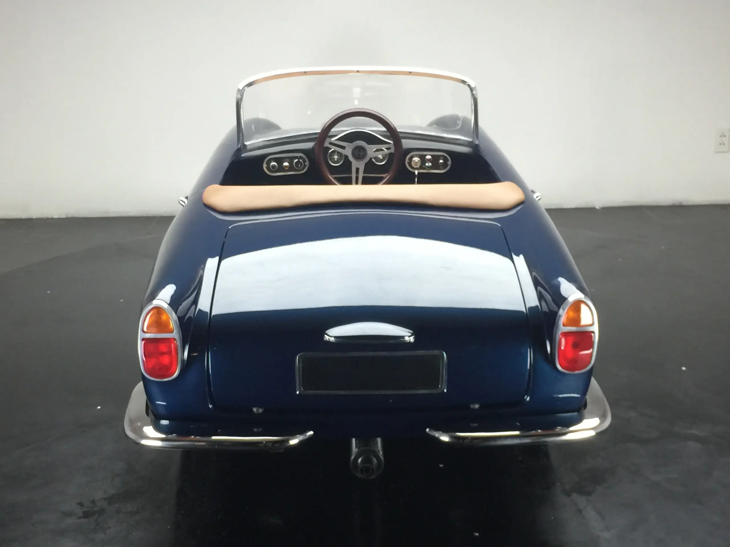 Das Bild zeigt die Rückansicht eines blauen GB Spirit Junior-Gran-Turismo mit beigem Sitz, klassischem Lenkrad und sportlichem Design.