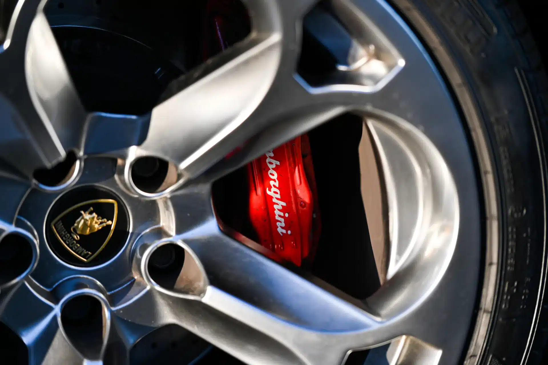 Rote Lamborghini-Bremssättel hinter einer silbernen Felge eines Murciélago, Nahaufnahme