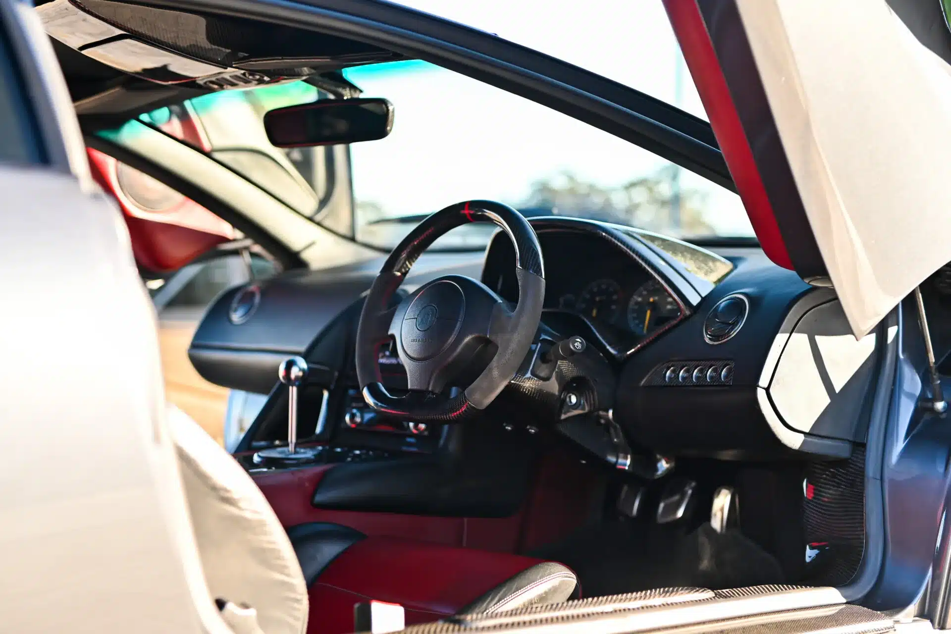 Innenaufnahme eines Lamborghini Murciélago, offenem Schaltgitter, Rechtslenker-Konfiguration und rot-schwarzem Interieur.