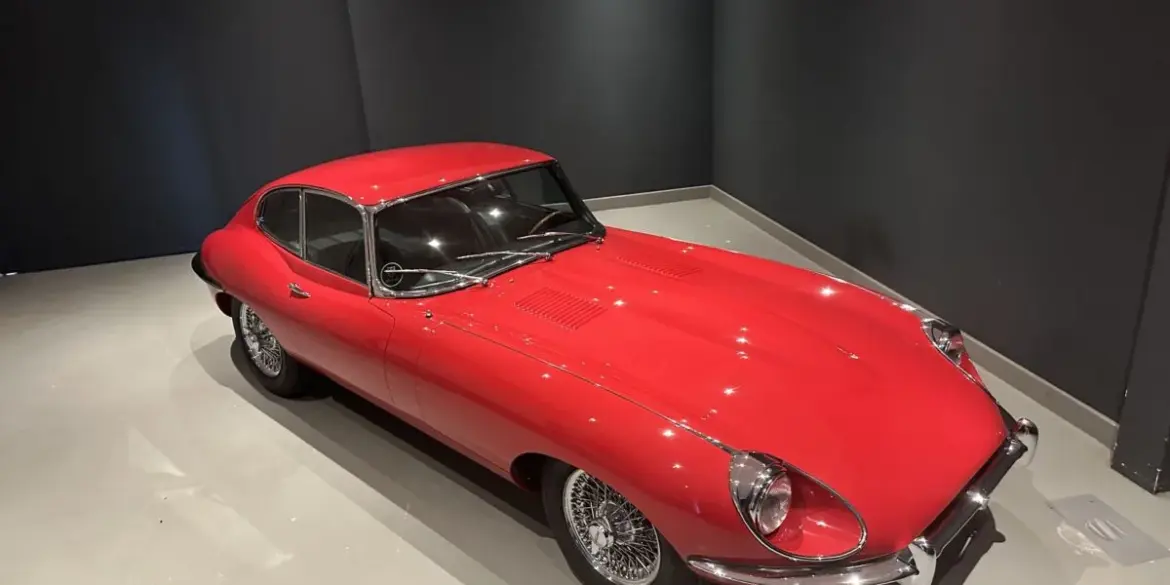 Roter Jaguar E-Type Coupé Serie I in einem Ausstellungsraum, Sicht von schräg oben.