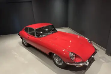 Roter Jaguar E-Type Coupé Serie I in einem Ausstellungsraum, Sicht von schräg oben.