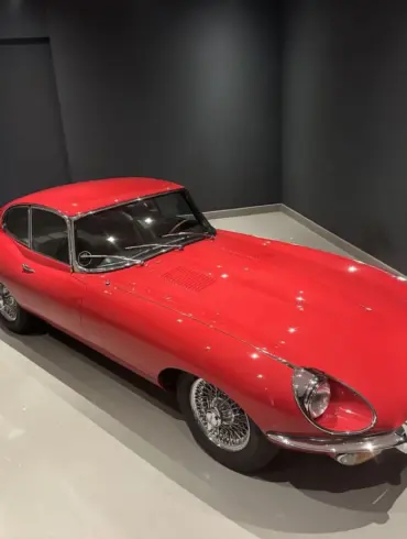 Roter Jaguar E-Type Coupé Serie I in einem Ausstellungsraum, Sicht von schräg oben.