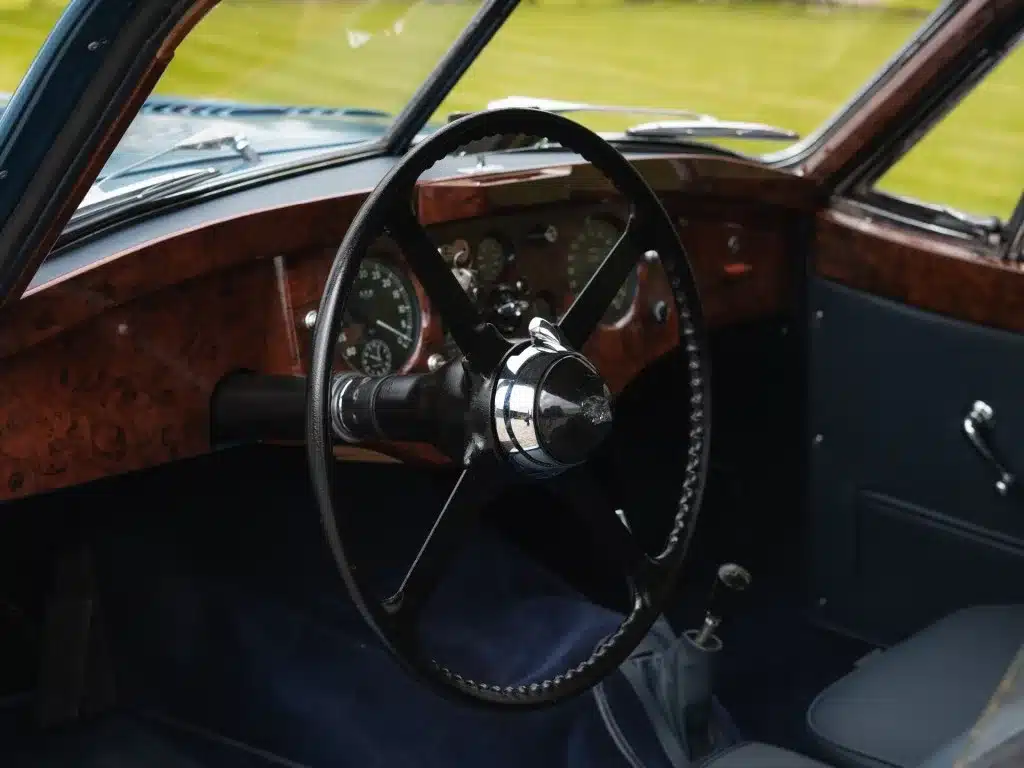 Innenraum eines Jaguar XK 120 FHC 1951 mit klassischem Holzarmaturenbrett, Rundinstrumenten und originalem Lenkrad.