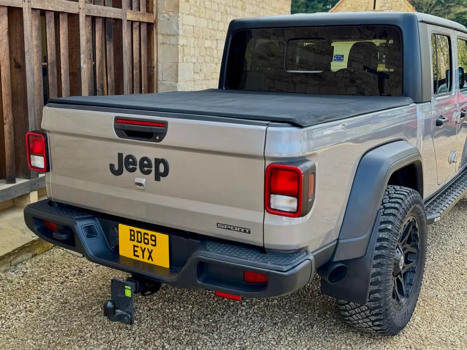 Jeep Gladiator 3.6 V6 Pick-up, Baujahr 2019/2020, in Grau Metallic mit schwarzer Hardtop-Abdeckung und UK-Kennzeichen, Heckansicht.