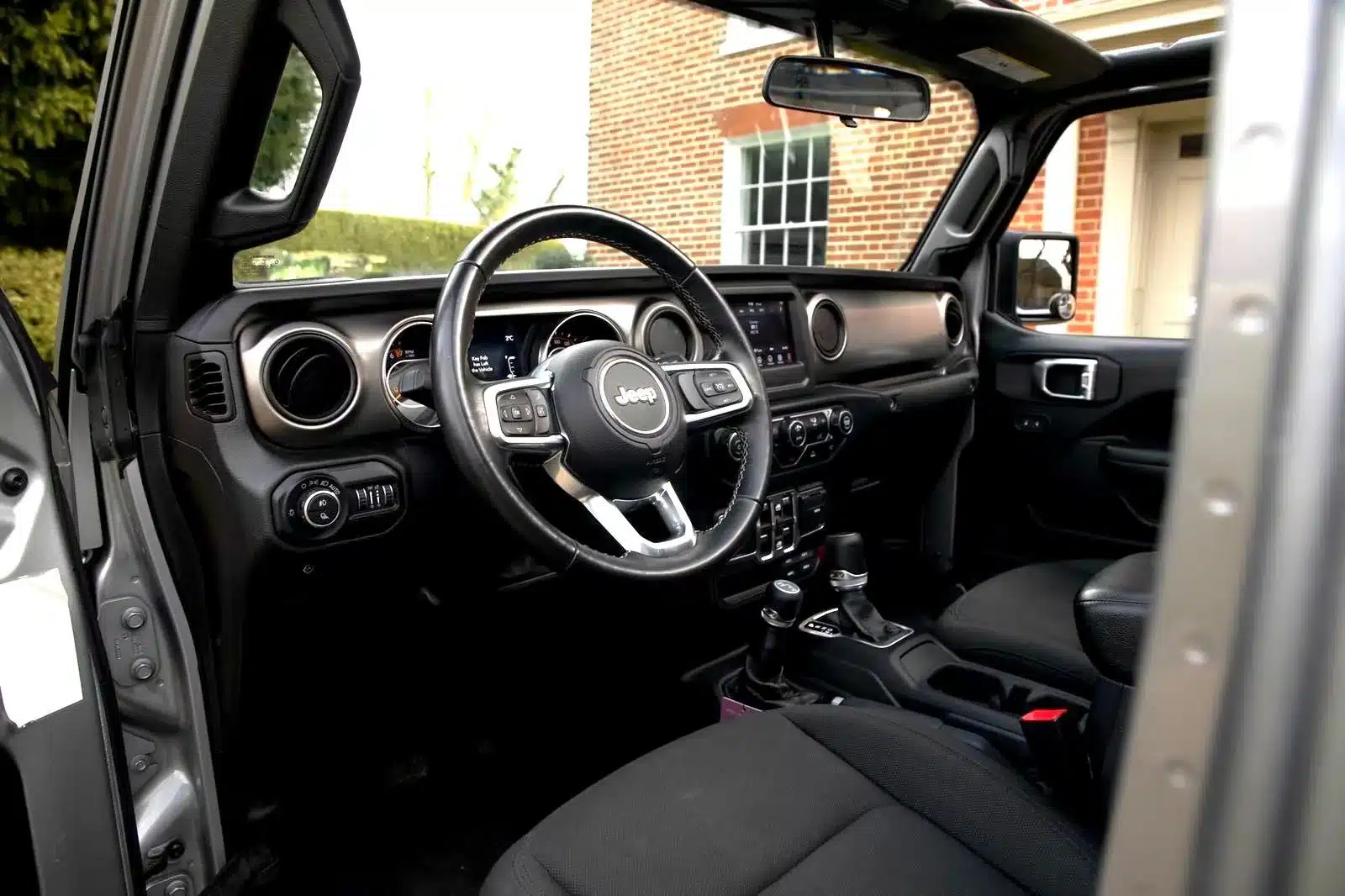 Blick in den Innenraum des Jeep Gladiator 3.6 V6 mit geöffnetem Fahrerfenster und sichtbarem Armaturenbrett.