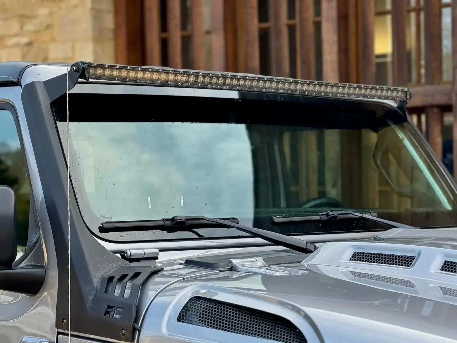 Detailaufnahme der Frontscheibe und Motorhaube eines Jeep Gladiator 3.6 V6 mit LED-Lichtleiste in Grau Metallic.