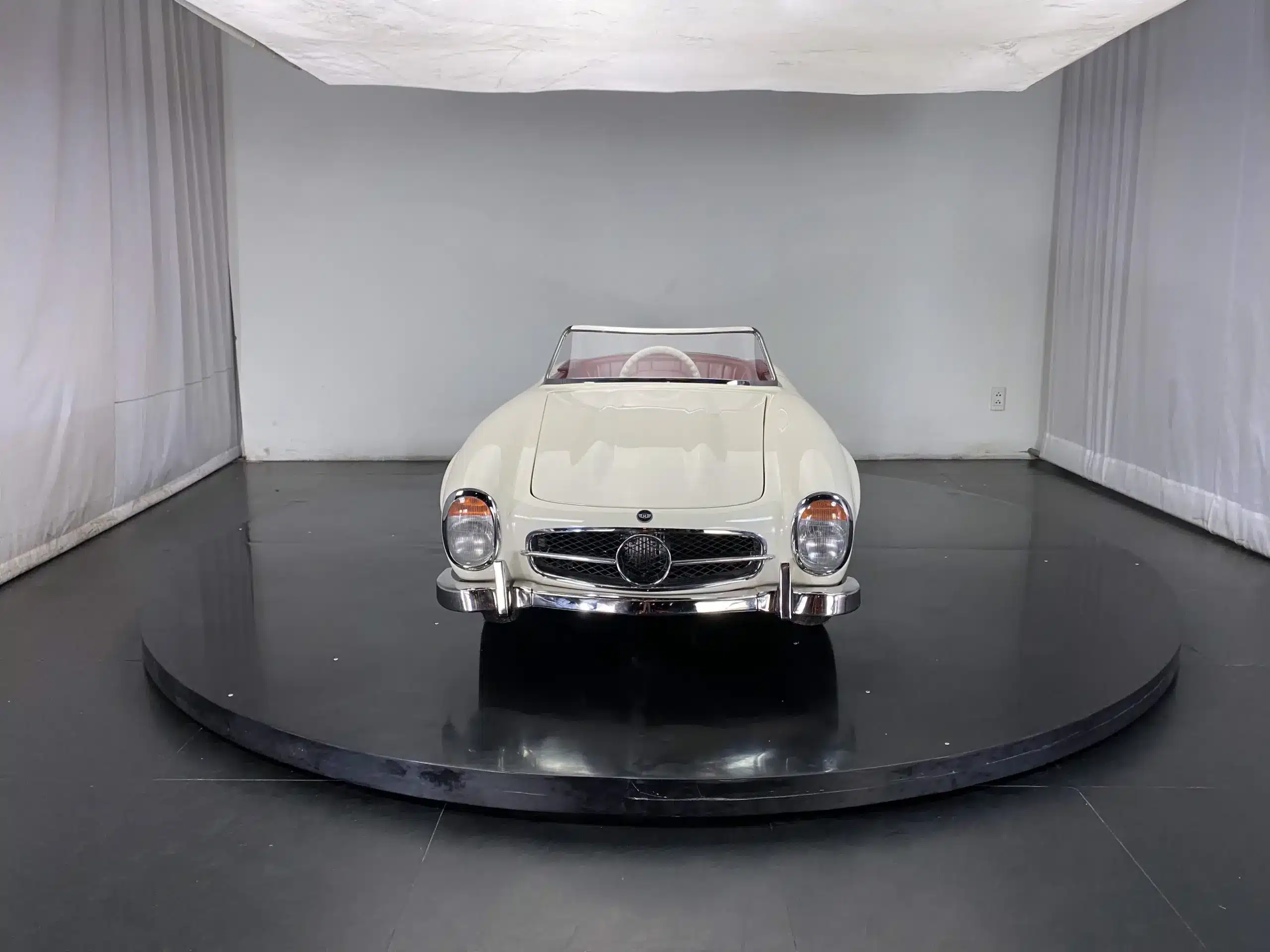 Hochwertiger Mini-Rennwagen im klassischen Design mit Frontansicht auf schwarzer Plattform.