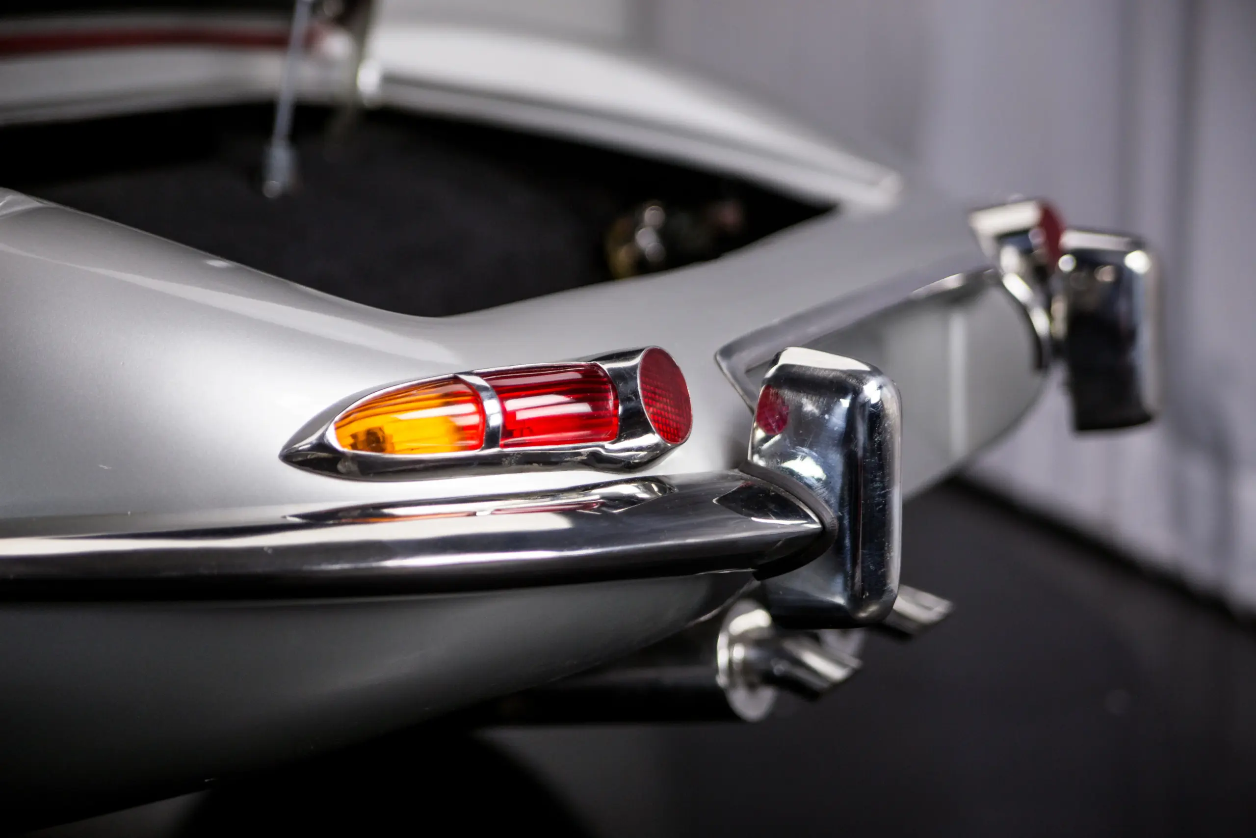 Nahaufnahme eines chromverzierten Heckabschlusses mit Rückleuchten und Stoßstange eines klassischen Autos