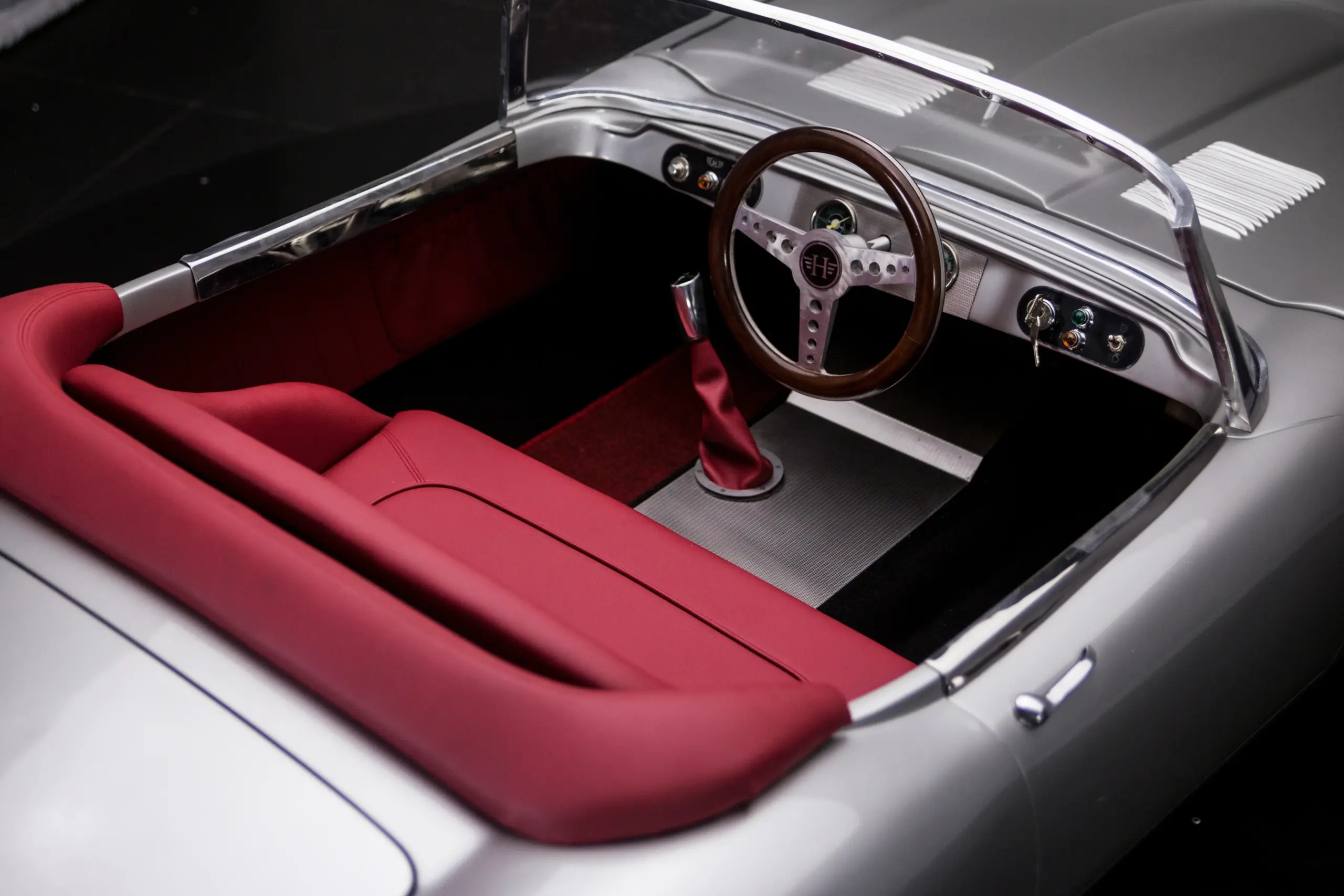 Innenraum eines Junior Series 1 mit rotem GFK-Sitz, Holzlenkrad und klassischen Bedienelementen