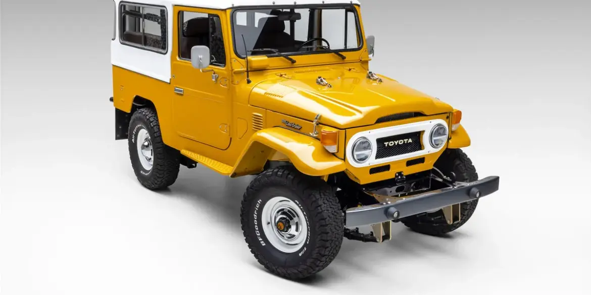 Restaurierter gelb-weißer Toyota Land Cruiser vor neutralem Hintergrund