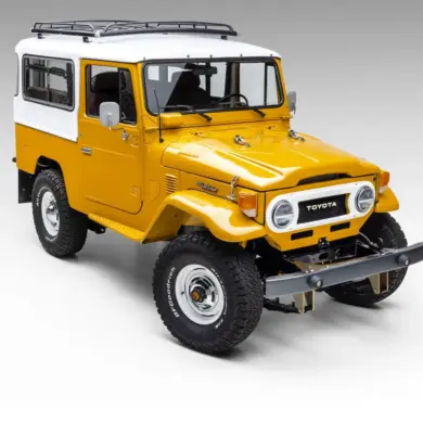 Restaurierter gelb-weißer Toyota Land Cruiser vor neutralem Hintergrund