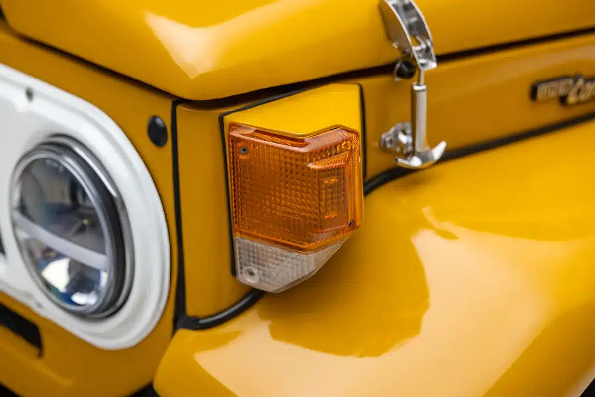 Detailaufnahme Blinker und Scheinwerfer eines restaurierten gelben klassischen Geländewagens