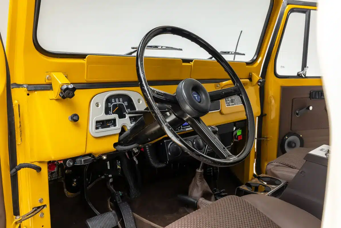 Innenraum eines gelben klassischen Geländewagens mit Detailaufnahme des Armaturenbretts, Lenkrads und Sitzbereichs