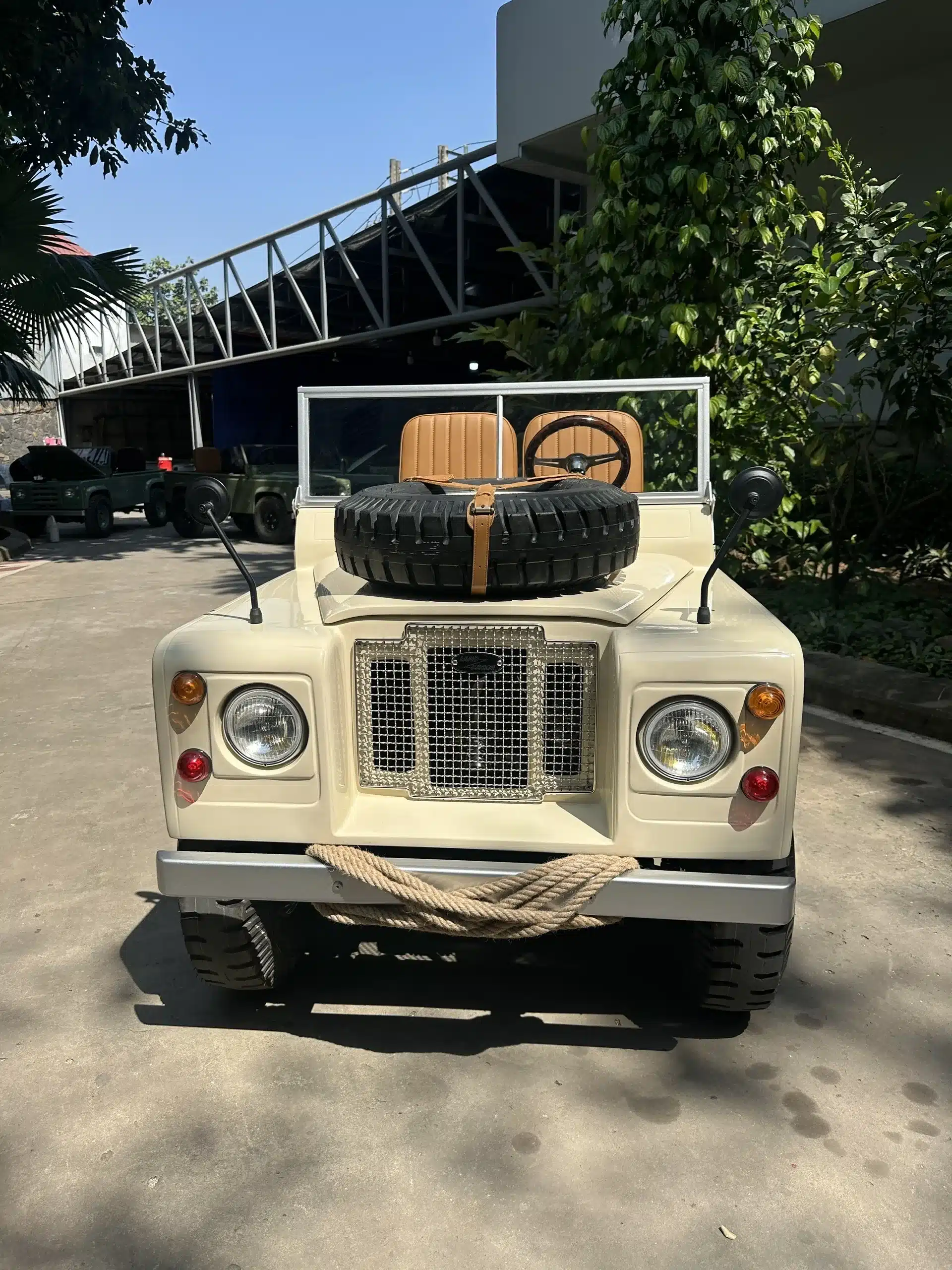 Der Land Junior: Kinderfahrzeug im Stil eines klassischen Offroaders, frontal fotografiert mit Ersatzrad auf der Motorhaube und braunen Sitzen.
