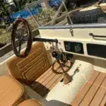 Innenansicht des Land Junior mit Lenkrad, Schalthebel, Pedalen und beigen Ledersitzen in Detailaufnahme.