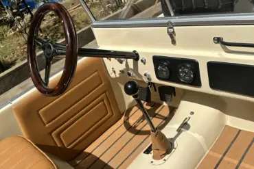 Innenansicht des Land Junior mit Lenkrad, Schalthebel, Pedalen und beigen Ledersitzen in Detailaufnahme.