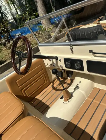 Innenansicht des Land Junior mit Lenkrad, Schalthebel, Pedalen und beigen Ledersitzen in Detailaufnahme.