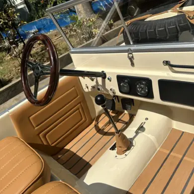 Innenansicht des Land Junior mit Lenkrad, Schalthebel, Pedalen und beigen Ledersitzen in Detailaufnahme.
