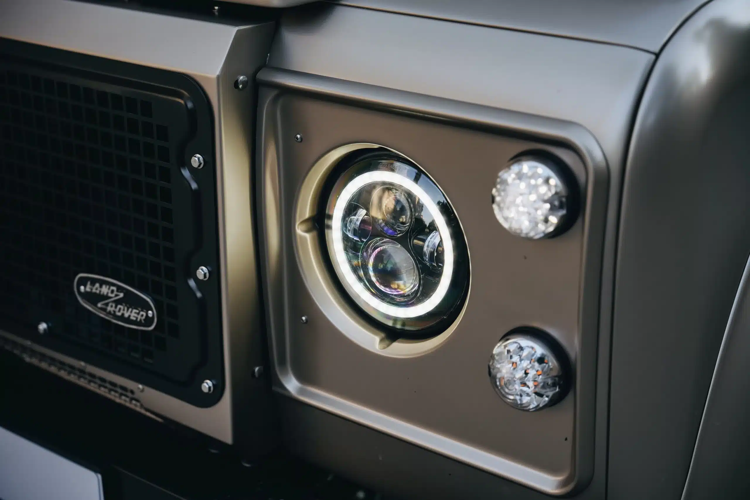 Frontscheinwerfer, Blinker und Grill eines Land Rover Defender 110 (1991) mit LED-Technik in Beige Mica.