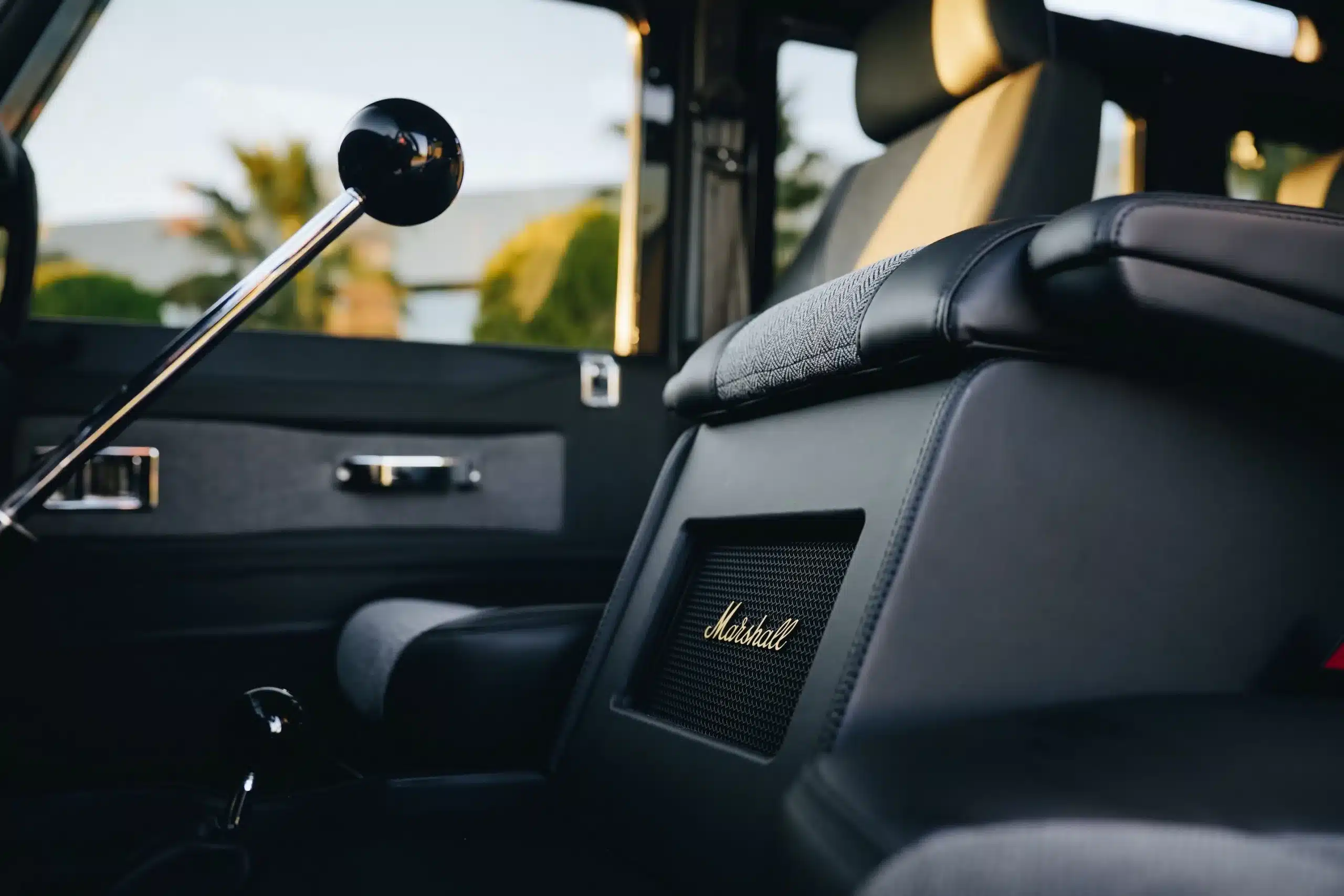 Innenraum eines Land Rover Defender 110 (1998) mit Lederausstattung und Marshall Lautsprecher im Fokus.