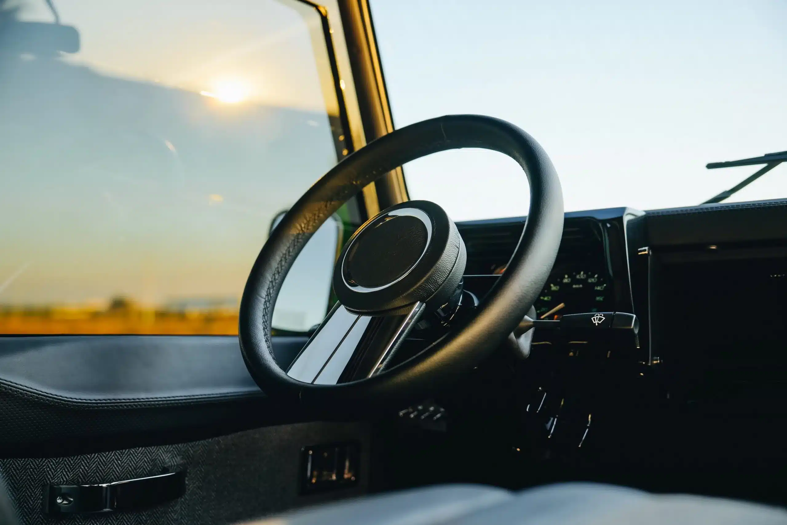 Innenansicht mit Fokus auf Lenkrad und Armaturen Land Rover Defender 110, Modell 1998.