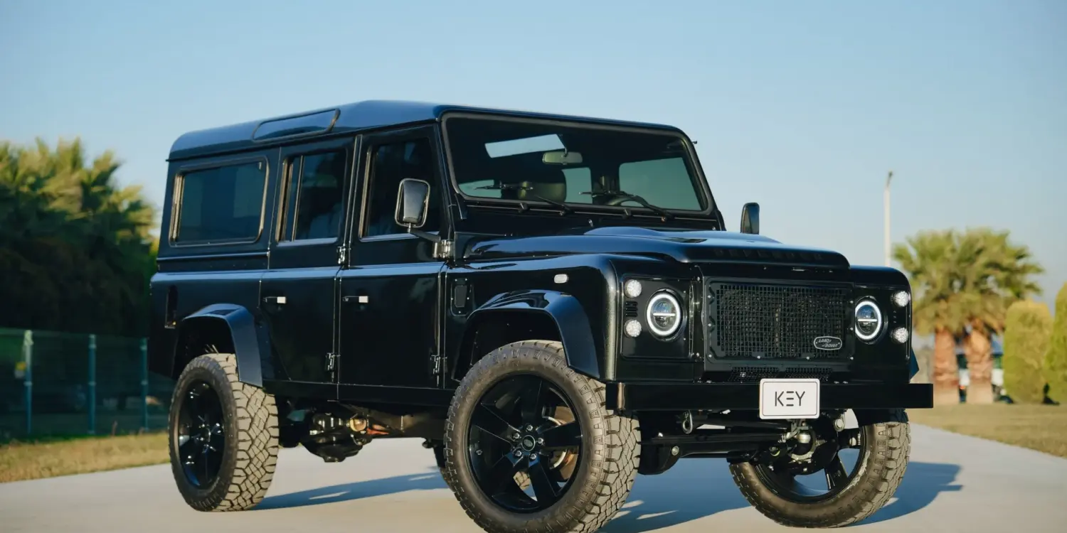 Schwarzer Land Rover Defender 110 300Tdi Baujahr 1998 mit LED-Scheinwerfern, 20-Zoll-Rädern und markanter Offroad-Optik im Freien.