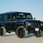 Schwarzer Land Rover Defender 110 300Tdi Baujahr 1998 mit LED-Scheinwerfern, 20-Zoll-Rädern und markanter Offroad-Optik im Freien.