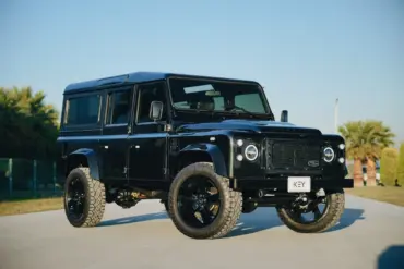 Schwarzer Land Rover Defender 110 300Tdi Baujahr 1998 mit LED-Scheinwerfern, 20-Zoll-Rädern und markanter Offroad-Optik im Freien.